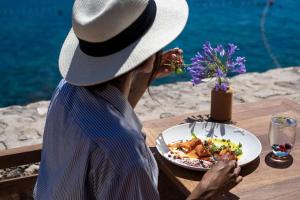 a person wearing a hat sitting at a table with a plate of food at Rixos Premium Dubrovnik in Dubrovnik