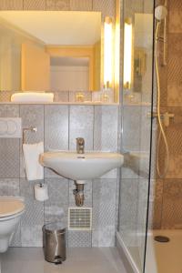 W łazience znajduje się umywalka i prysznic. w obiekcie Hôtel des Arcades de Cachan - Grand Paris Sud w mieście Cachan