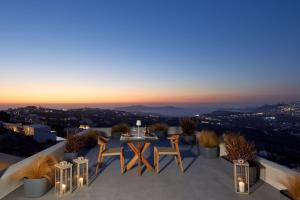 a patio with a table and chairs at night at Arxegono Cave Houses Santorini in Pirgos