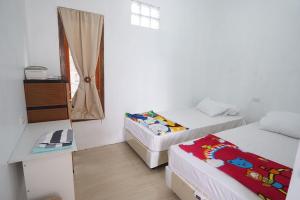 BihaにあるSapu Nyapah Losmen Syariah Tanjung Setiaのベッド2台と窓が備わる小さな客室です。