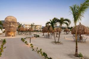 a beach with a statue of a head and palm trees at Wyndham Santa Marta Aluna Beach in Santa Marta