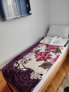 a bed with a purple and white blanket on it at Motel BI in Bijeljina