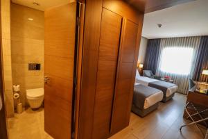 a bathroom with a toilet and a bed in a room at Holiday Inn Bursa - City Centre by IHG in Bursa
