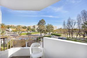 a white chair on a balcony with a view of a street at Praia da Rocha Mar Guest House in Portimão