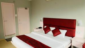 a bedroom with a red and white bed with red pillows at Hotel Meadows view in Manāli