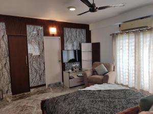 a bedroom with a bed and a chair and a television at The Beach House in Chennai