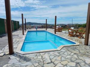 een zwembad op een patio met een tafel en stoelen bij Chale vista do Porto Imbituba com piscina in Imbituba