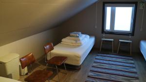 BorðeyriにあるTangahús Guesthouseのベッド1台、椅子、窓が備わる小さな客室です。