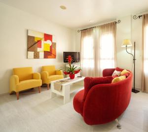 アルカラ・ラ・レアルにあるHotel Torrepalmaのリビングルーム(赤いソファ、黄色い椅子2脚付)