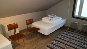 a room with a bed with two chairs and towels at Tangahús Guesthouse in Borðeyri