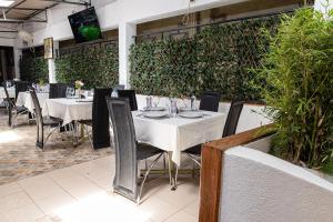 a restaurant with white tables and chairs and plants at The Stand Leisure Hotel in Nairobi