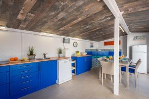 a kitchen with blue cabinets and a dining table at Villa Anais - PlusHolidays in Calpe