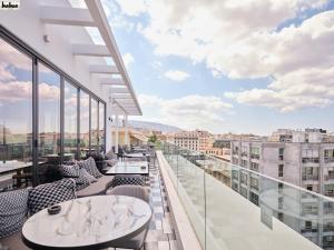 einen Balkon mit Tischen und Stühlen und Stadtblick in der Unterkunft NYX Esperia Palace Hotel Athens by Leonardo Hotels in Athen