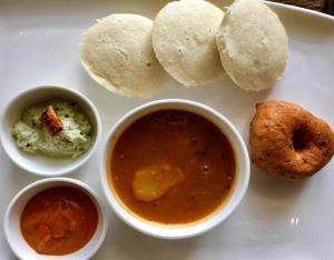 a white plate with bowls of food and dipping sauce at Grand Dyad Hotel - Near Kokilaben Hospital Andheri West in Mumbai