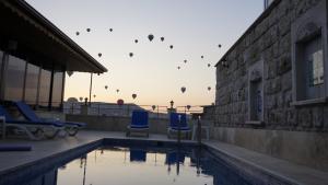 a swimming pool with two blue chairs and a building at Balloon Cave Hotel in Göreme