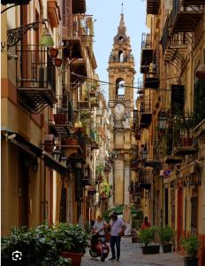 a group of people walking down a street with a clock tower at La Premiere Suite - Teatro Massimo Palermo in Palermo