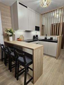 a kitchen with a island with chairs and a counter top at Pine Point Apartament with shared Pools, Jacuzzi, Sauna & Gym in Szklarska Poręba