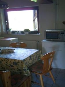 Il comprend une cuisine équipée d'une table, de chaises et d'un four micro-ondes. dans l'établissement Ferienwohnung Thomsen, à Taarstedt