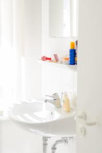 a bathroom with a white sink and a shelf at Appartementhaus Villa Norden in Kühlungsborn