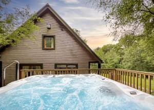 a hot tub on a deck next to a house at Ramshorn Estate Woodland Lodges in Oakamoor