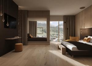 a bedroom with a large bed and a large window at Excelsior Dolomites Life Resort in San Vigilio Di Marebbe