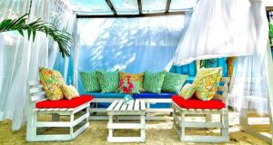 a blue couch with colorful pillows and two chairs at Summer beach hotel in El Charquito