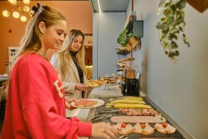 dos mujeres de pie en una cocina preparando comida en Hotel Halbert, en Groninga
