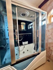 ein Badezimmer mit einer Badewanne und einer Glaswand in der Unterkunft Airport Lux Rooms in Kiembi Samaki