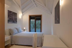 a white bedroom with a bed and a window at In Barreta in Barcelos