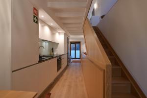 a hallway leading to a kitchen with a wooden staircase at In Barreta in Barcelos