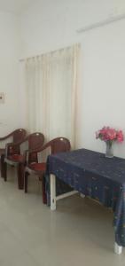 a room with a table and chairs and a vase of flowers at Jestine Homestay in Cochin