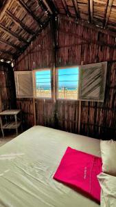 1 dormitorio con 1 cama en una cabaña con 2 ventanas en El Viejo Moi Hospedaje & Restaurante, en Cabo de la Vela