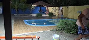 a person standing next to a swimming pool at Casa para Carnaval coruripe c/ piscina perto da praia in Coruripe