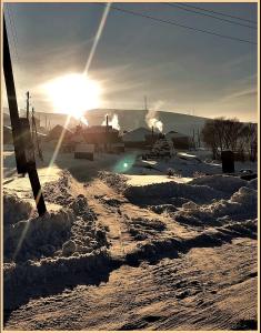 una carretera cubierta de nieve con el sol en el fondo en HERBS & HONEY boutique hotel & restaurant, 