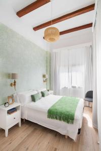 a bedroom with a white bed with a green blanket at Casa de Playa Ideal para familias in Arenys de Mar