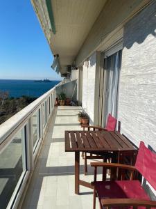 - un balcon avec une table et des chaises en bois et l'océan dans l'établissement Serene Apartment with Breathtaking Sea View, à Thessalonique