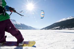 a person on a snowboard holding a kite in the snow at Hotel Alpenrose in San Valentino alla Muta
