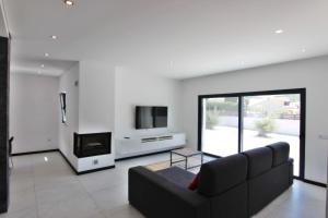 a living room with a black couch and a tv at Villa Goncinha - Piscina in Loulé