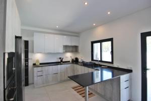 a kitchen with white cabinets and a black counter top at Villa Goncinha - Piscina in Loulé