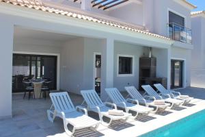 a group of chairs sitting next to a swimming pool at Villa Goncinha - Piscina in Loulé
