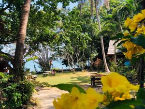 un parque con mesa de picnic, árboles y flores amarillas en Sabai Corner Bungalows - SHA Extra Plus, en Ko Yao Noi