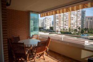 een balkon met een tafel en stoelen en een groot raam bij Benimar 1 in Cala de Finestrat