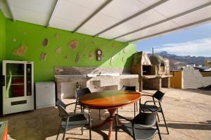 eine Terrasse mit einem Tisch und Stühlen sowie einer grünen Wand in der Unterkunft Villa Paraiso Aldeano 1 in San Nicolás