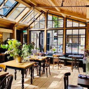 um restaurante com mesas e cadeiras de madeira e janelas em Royal Oak Ramsden em Ramsden