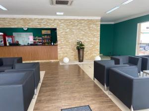 a waiting room with blue chairs and green walls at Perola Verde Hotel in Birigui