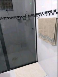 um chuveiro com uma porta de vidro e uma toalha em Hospedagem no Sul de Florianópolis em Florianópolis