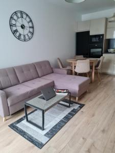 sala de estar con sofá y mesa con ordenador portátil en Airport Apartment en Varsovia