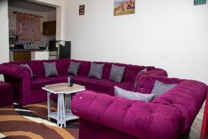 a purple couch in a living room with a table at Denverwing Homes in Eldoret