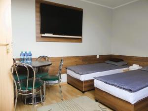 a room with two beds and a table and a tv at ZAJAZD SKRZETUSKI in Wojcieszków