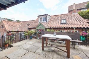 uma mesa de piquenique de madeira em frente a uma casa em Abbey View Cottage em Whitby